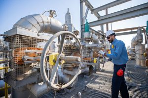 Workers wearing flame-retardant clothing safely operate machinery.